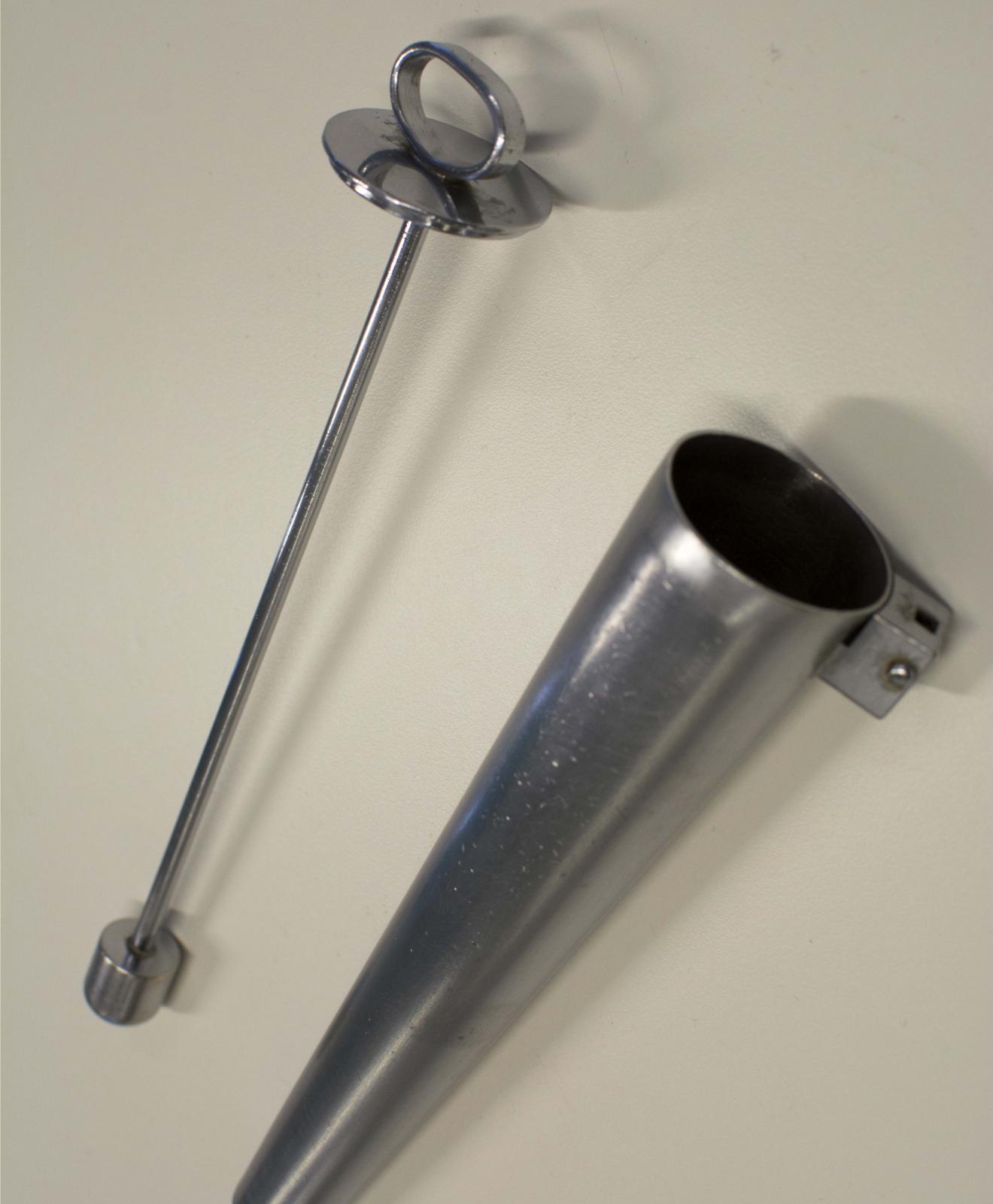 Instrumento metálico con forma de cono en cuyo interior se inserta una varilla con una anilla en un extremo y un tope cilíndrico también metálico en el opuesto