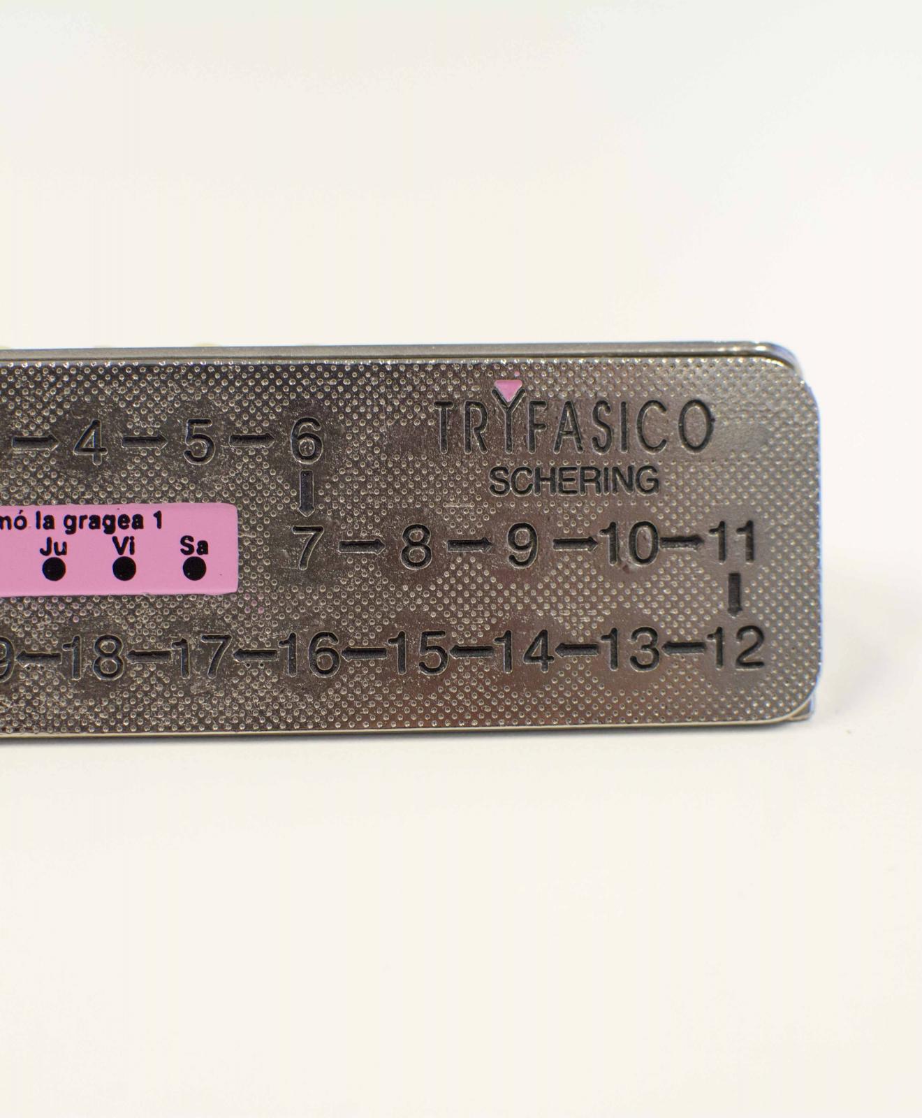 Pieza metálica rectangular con numeración incisa del 1 al 21 y un calendario semana. El número 1 y el calendario semanal están enmarcados en rosa