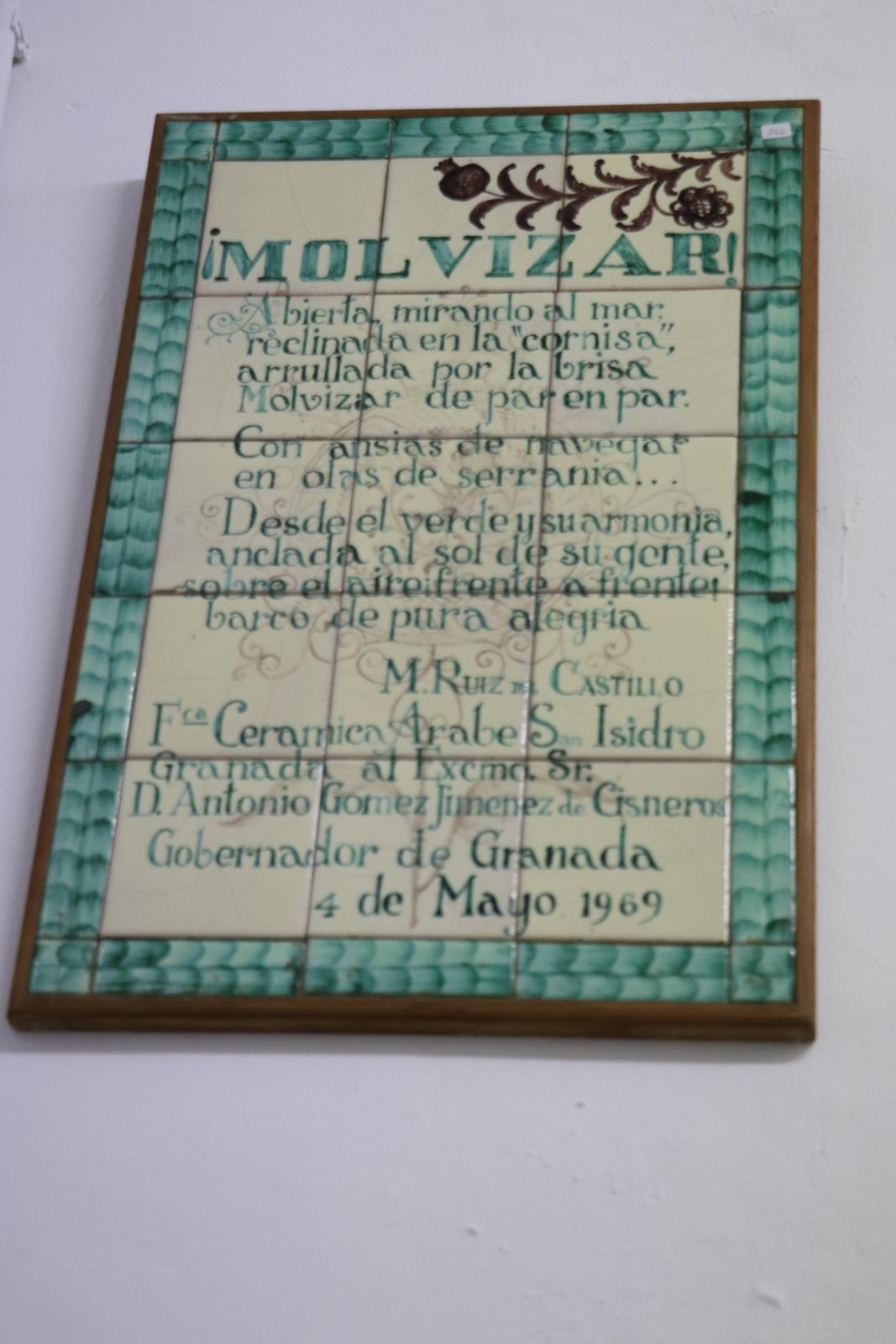 Placa con laudatio a la localidad de Molvízar formada por cuadradas piezas de cerámica, enmarcada por una franja verde de piezas de cerámica estrechas