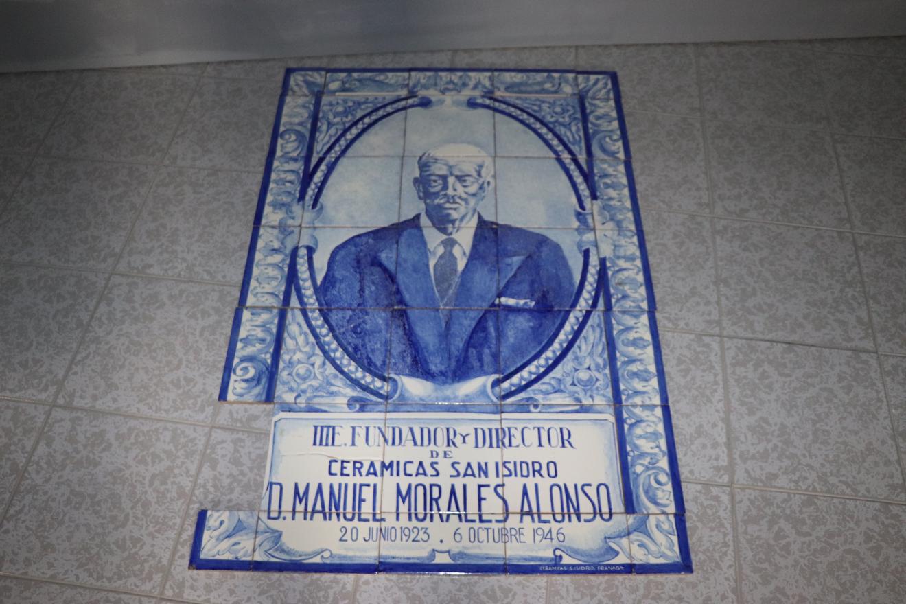 Paño de azulejos con retrato masculino enmarcado en formas geométricas y decoración vegetal con cartela de texto