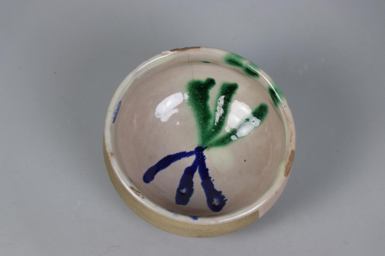 Pieza de cerámica granadina con forma de cuenco, esmaltada en blanco y en cuyo interior se realiza decoración esquemática en azul y verde