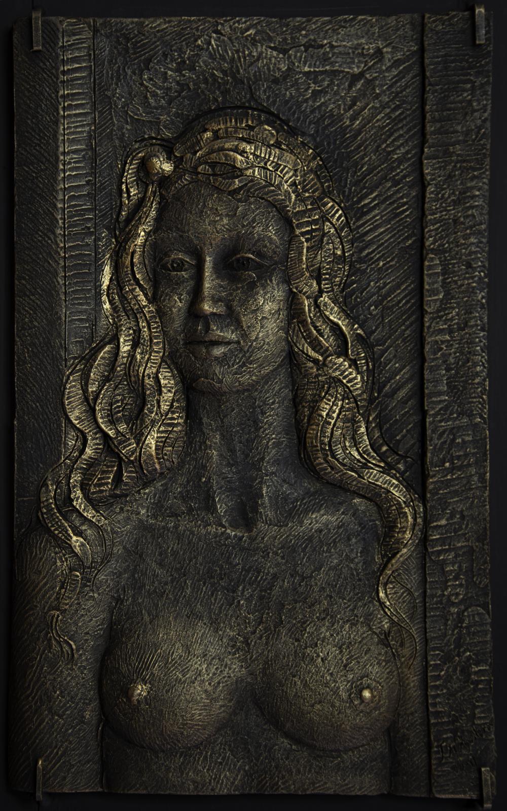 Vista frontal de un retrato femenino desnudo, de busto, en un relieve de metal