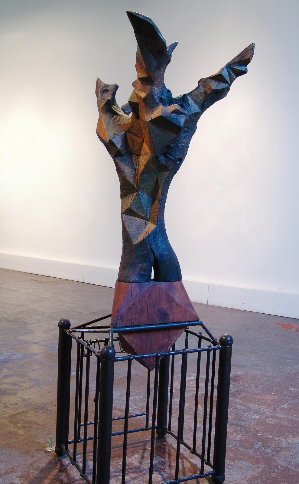 Escultura de bulto redondo sobre una peana formada por una estructura cúbica de reja negra con refuerzo en las esquinas